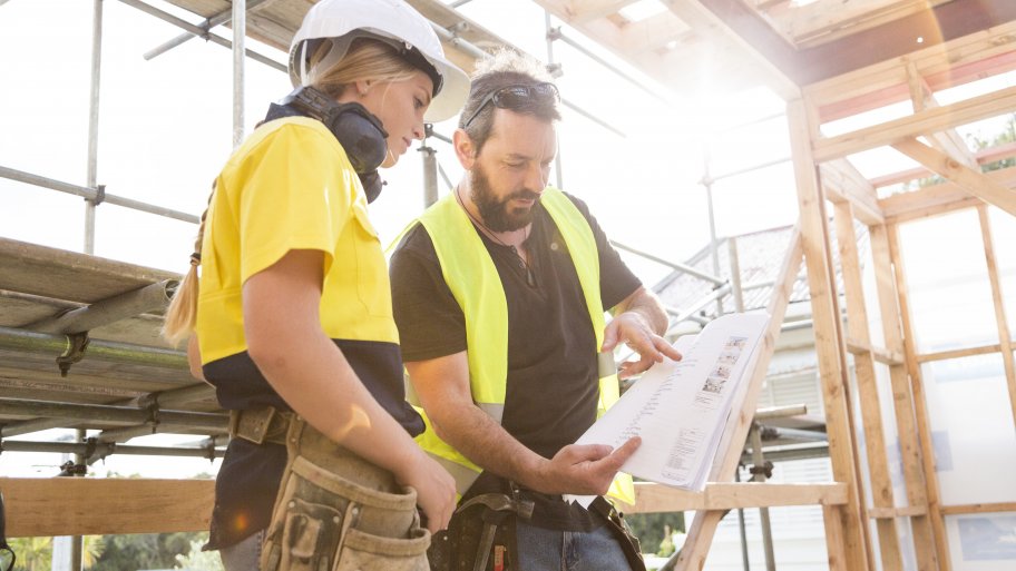 two homebuilders reviewing blueprints in a home being built
